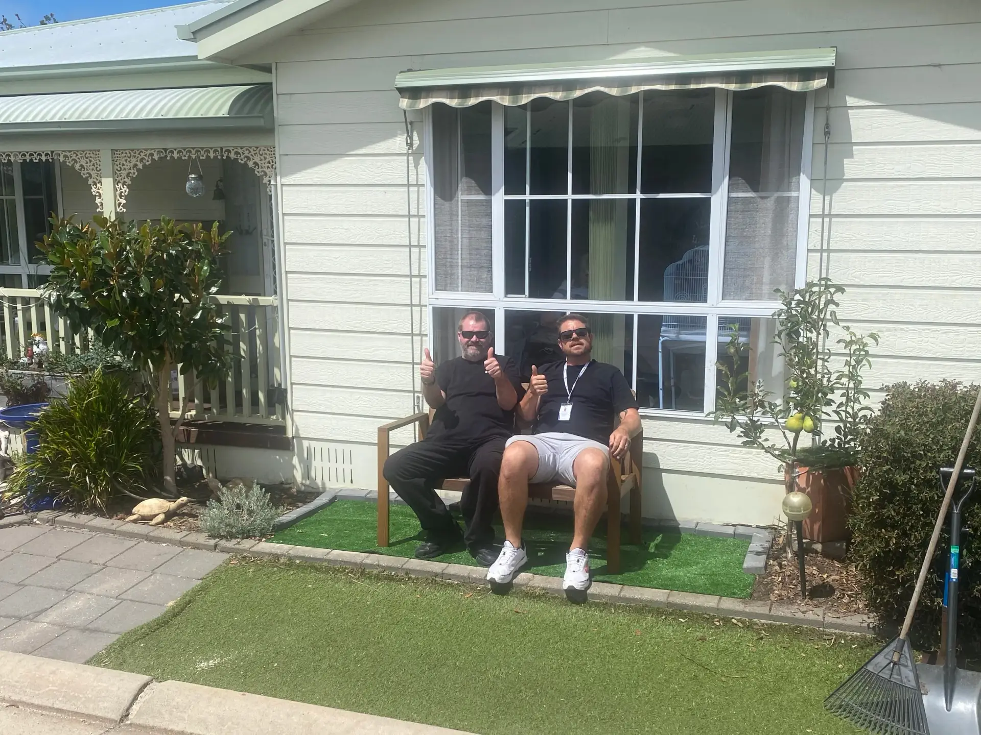 A participant and support worker relaxing together on a porch