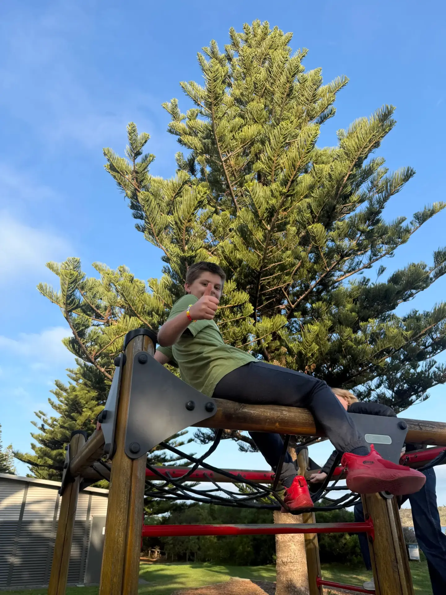 A participant giving a thumbs up while climbing at the playground